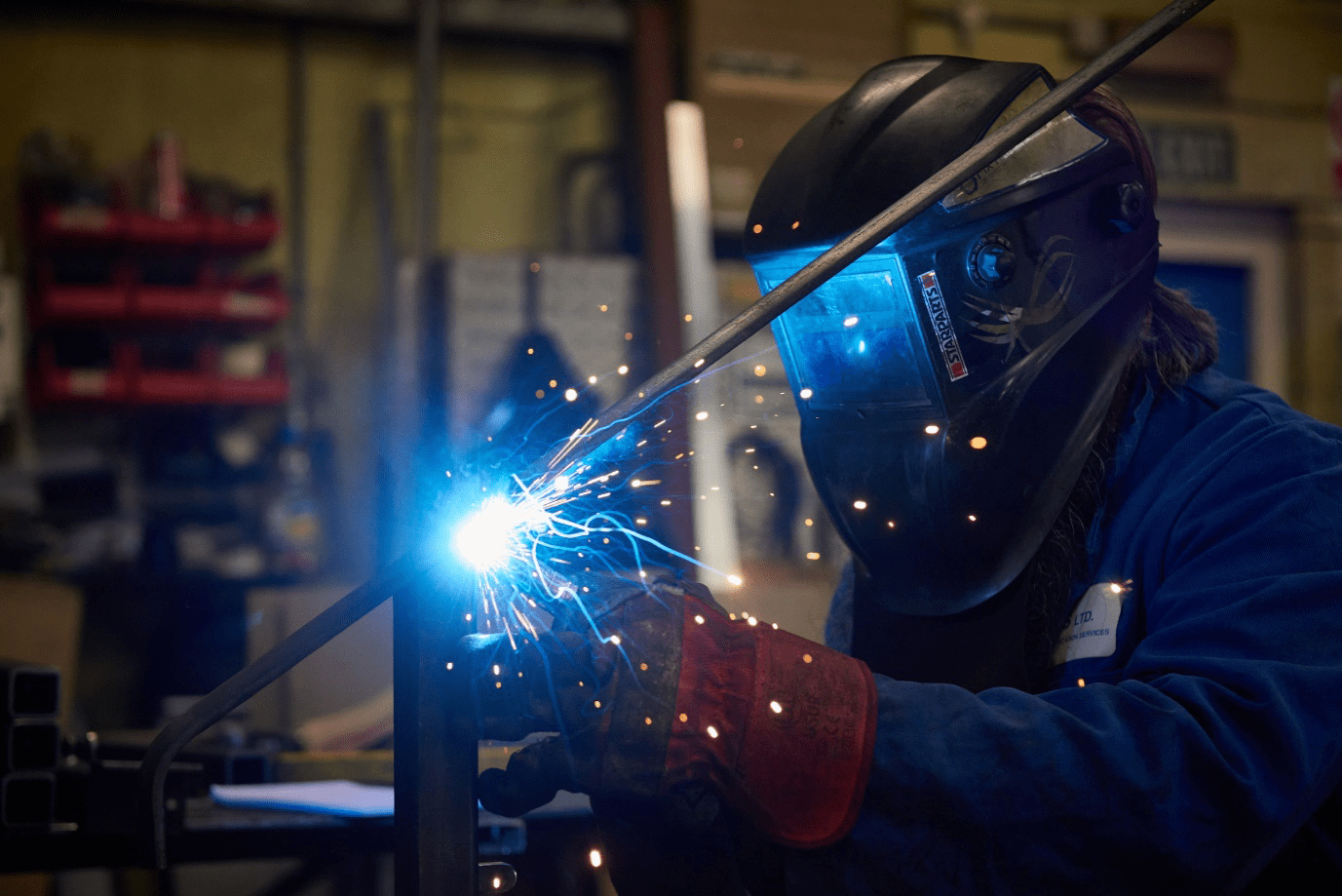 Person welding in factory blue sparks